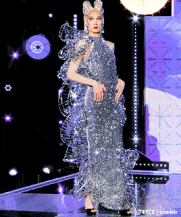 a woman is walking down a runway wearing a silver dress