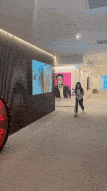 a woman riding a scooter in a hallway with a painting of a man on the wall behind her that says no