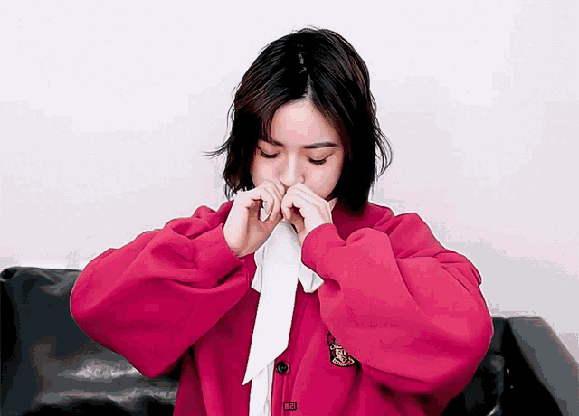a woman wearing a red jacket and a white bow tie is covering her nose