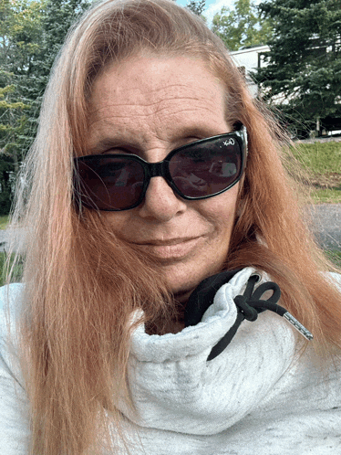 a woman wearing sunglasses and a white sweater with a black zipper