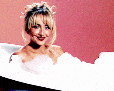 a woman is taking a bath in a tub filled with bubbles