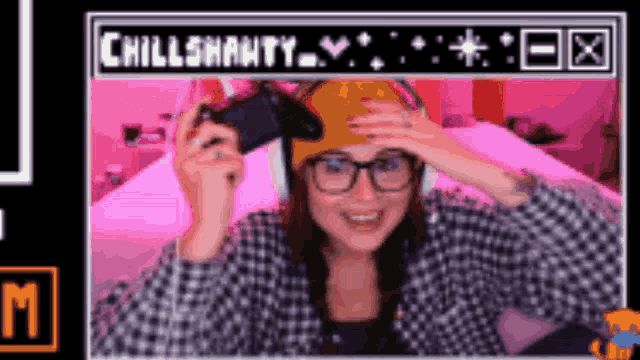 a woman wearing glasses and a beanie is holding a video game controller in front of a screen that says chillshawnty