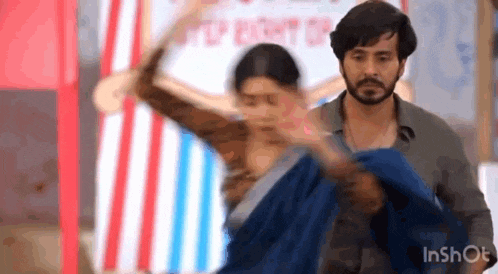 a man is holding a woman in his arms while they are dancing in a room .