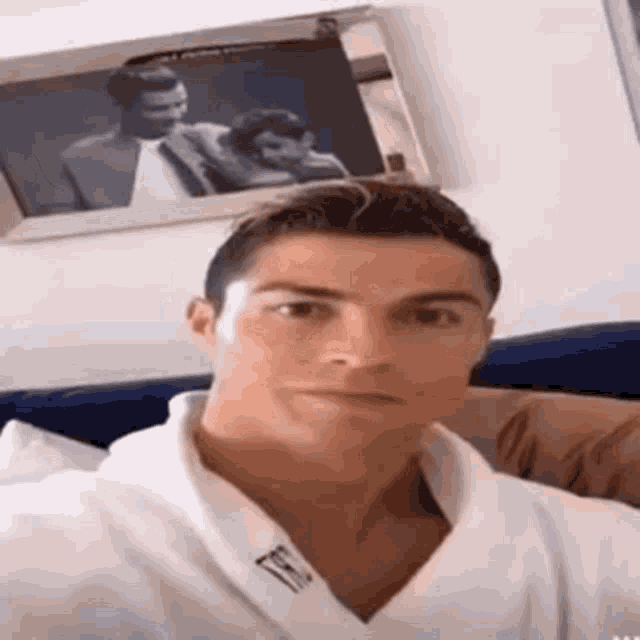 a man in a white robe is taking a selfie in front of a picture of two men