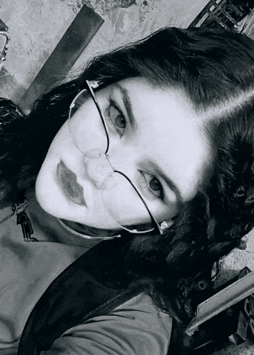 a black and white photo of a girl wearing glasses and a black shirt