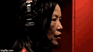 a woman wearing headphones is singing into a microphone with imgflip.com at the bottom