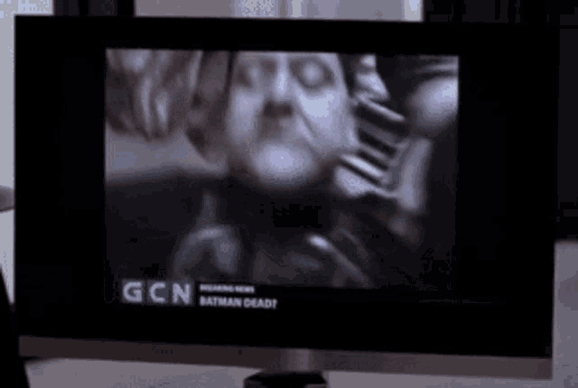 a tv screen shows a man with a beard and the words gcn batman dead