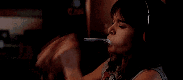 a young girl is brushing her teeth with a toothbrush and headphones .