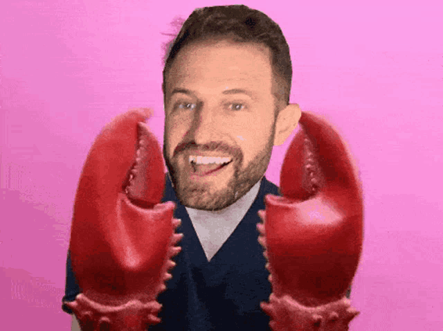 a man with a beard is holding a lobster claws in front of his face