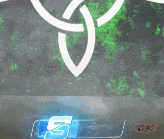 a man with a beard is standing in front of a tnlw logo