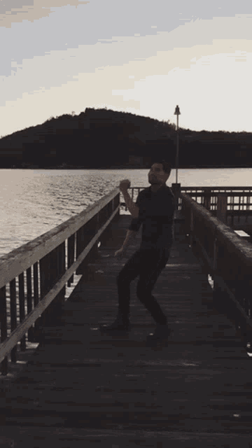 a man standing on a dock holding a ball in his hand