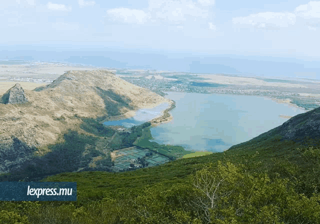 a large lake surrounded by mountains and trees with the words lexpress.mu in the corner