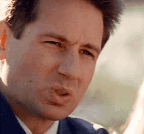 a man in a suit and tie is making a funny face with his mouth open .