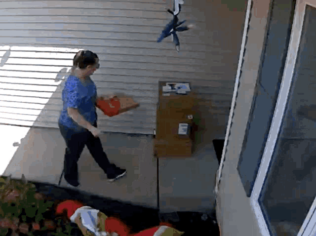 a woman in a blue shirt is carrying a box that says usps
