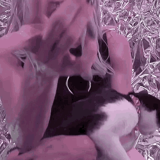 a woman is holding a black and white cat .