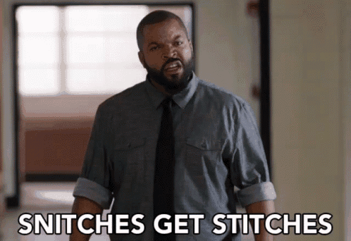 a man in a gray shirt and black tie is standing in a hallway and says snitches get stitches