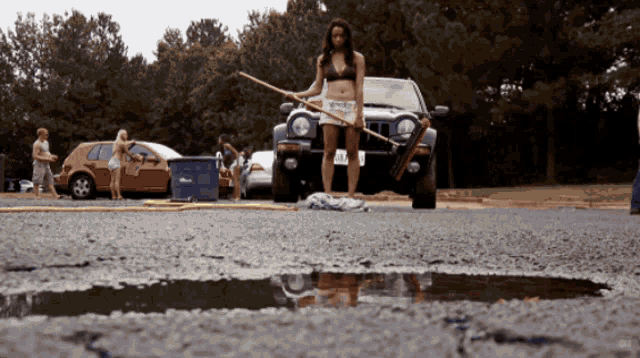 a woman in a bikini is standing in front of a jeep with a license plate that says aa - 666