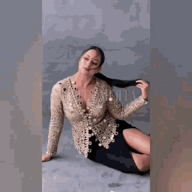 a woman is sitting on the floor wearing a very revealing top .