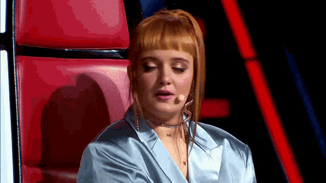 a woman with red hair is sitting in a red chair with her eyes closed