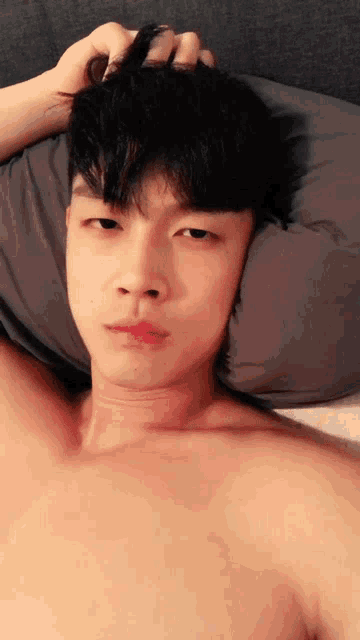 a man without a shirt is laying on a bed