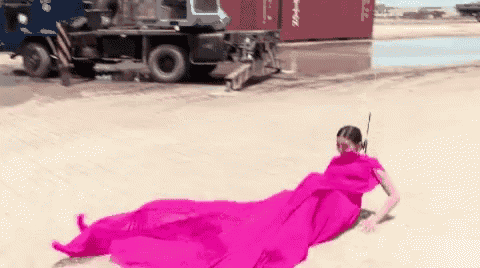 a woman in a long pink dress is laying on the ground next to a truck .