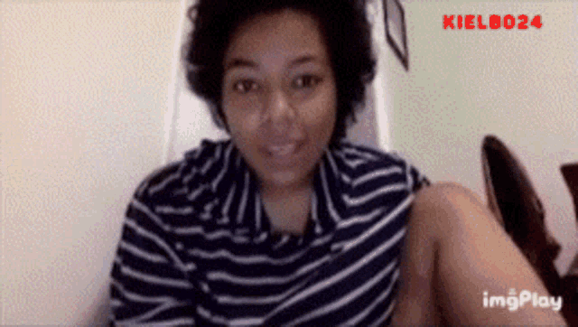 a woman in a blue and white striped shirt is sitting in a chair with the name kielb024 on the bottom