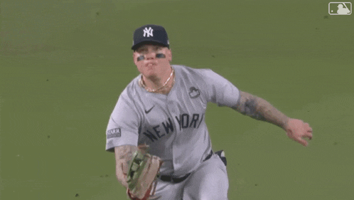 a man wearing a ny hat is laying on the grass