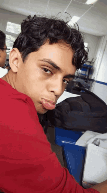a young man sticking his tongue out in a red shirt