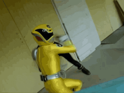a yellow power ranger is holding a sword in his hand