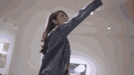 a woman in a denim jacket is taking a selfie in an art museum .