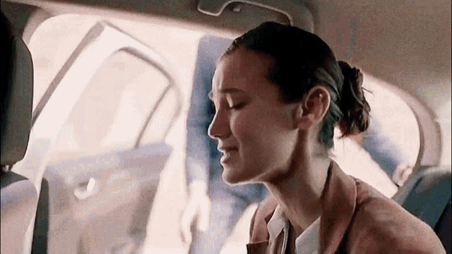 a woman is sitting in the back seat of a car with her eyes closed .