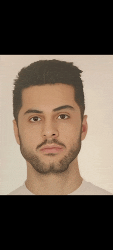 a man with a beard is wearing a white shirt and looking at the camera