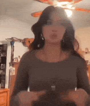 a woman is standing in front of a ceiling fan in a living room .