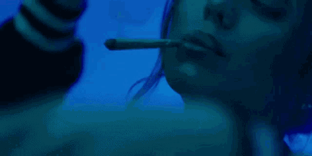 a woman is smoking a cigarette in a dark room .