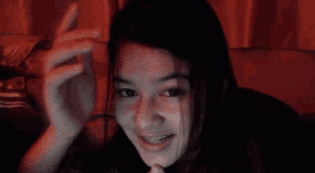a close up of a woman 's face with a red curtain in the background
