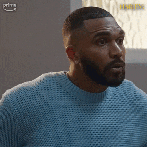 a man with a beard is wearing a blue sweater and earrings