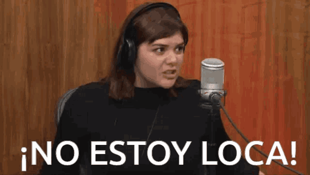 a woman wearing headphones is sitting in front of a microphone with the words no estoy loca written below her
