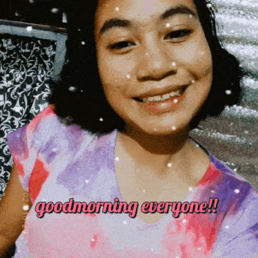 a girl in a tie dye shirt smiles and says good morning everyone