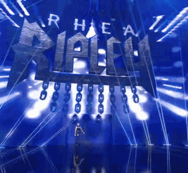 a man stands in front of a stage with a sign that says ' r hea ' on it
