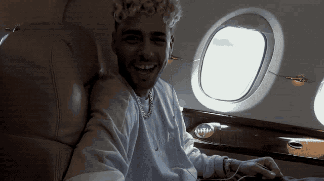a man wearing a nike sweatshirt sits in an airplane seat