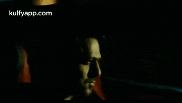 a man is sitting in a car in the dark and looking out the window .