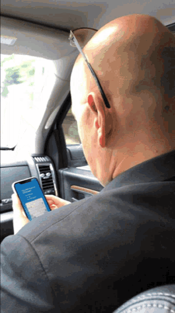 a man sitting in a car looking at a cell phone