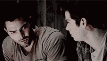 two men are sitting next to each other and looking at each other .