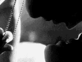 a black and white photo of a couple kissing each other .