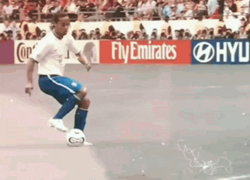 a soccer player kicks a soccer ball in front of a fly emirates sign
