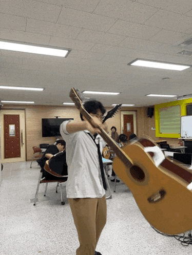 a man holds a guitar over his head in a room