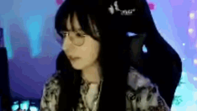 a woman wearing glasses is sitting in a chair in front of a computer screen .
