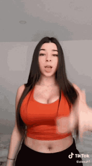 a woman in a red crop top and black shorts is dancing on tiktok .