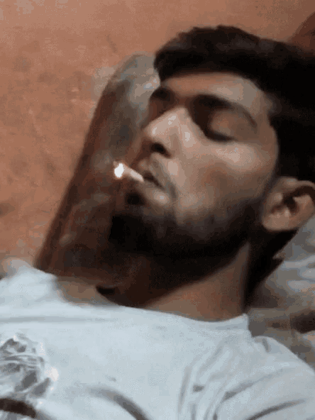 a man with a beard is smoking a cigarette while laying down