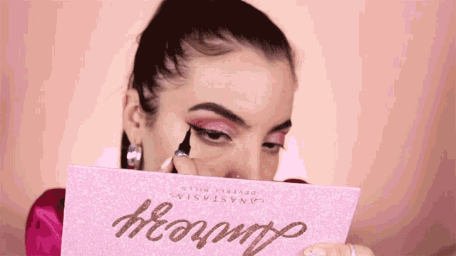 a woman is applying makeup to her face while holding a palette that says groovy